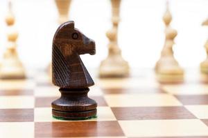 Preto cavaleiro contra branco xadrez peças em borda foto