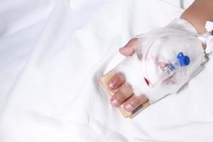 mão do bebê com curativo aplicando solução salina na cama do hospital foto