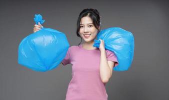jovem ásia mulher segurando Lixo saco em fundo foto