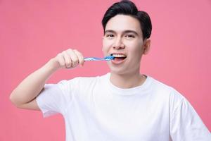 jovem ásia homem segurando escova de dente em fundo foto