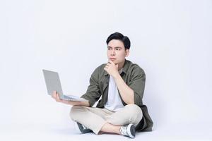 jovem ásia o negócio homem sentado e usando computador portátil em fundo foto