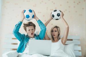 casal feliz assistindo futebol futebol na cama foto