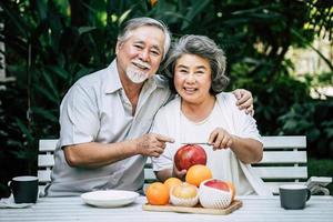 casal de idosos brincando e comendo frutas foto