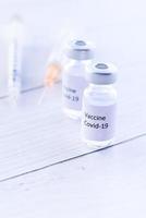 vacina de coronavírus e seringa em fundo branco foto