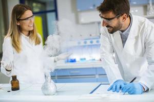 pesquisadores fazendo experimentos com fumaça em uma mesa de um laboratório químico