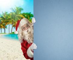 santa claus em uma tropical de praia com uma em branco espaço para seu texto foto