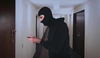 ladrao com balaclava tentativas para aberto a porta do apartamento com uma chave foto