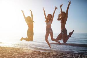 feliz sorridente amigos pulando às a de praia foto