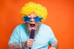 gordo homem com barba, tatuagens e oculos de sol canta uma música foto