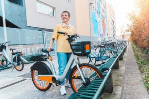 mulher leva uma alugado bicicleta dentro uma bicicleta estacionamento foto