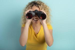 feliz menina parece com binocular algo. ciano fundo foto