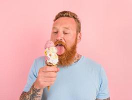 com fome homem com barba e tatuagens come uma grande sorvete foto