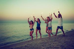 feliz sorridente amigos corrida às a de praia com espumante velas foto