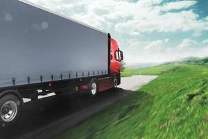 vermelho moderno caminhão comovente velozes em a estrada com natural panorama foto