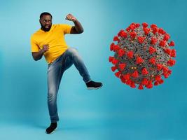 homem ataques com uma pontapé a coronavírus. azul fundo foto