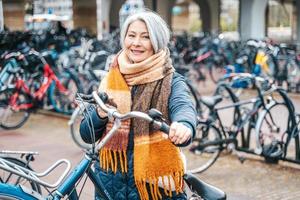 Senior mulher pega a bicicleta dentro uma estacionamento foto