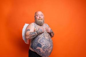 gordo espantado homem com barba , tatuagens e asas atos gostar a anjo foto