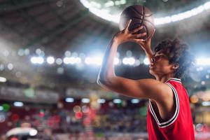 basquetebol jogador lança a bola dentro a cesta dentro a estádio cheio do espectadores. foto