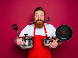 confuso chefe de cozinha com barba e vermelho avental é pronto para cozinhar foto