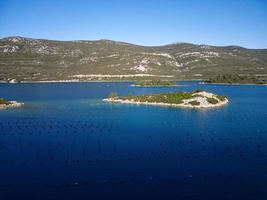 vista aérea do drone da baía de mali ston localizada na península de peljesac. fazendas de ostras na água do mar azul-turquesa. mistura única de água doce e água do mar. foto