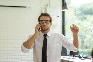 jovem empresário falando ao telefone enquanto trabalhava no escritório foto