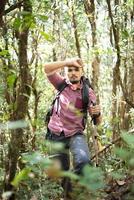 jovem caminhante ativo pela floresta em direção à montanha foto