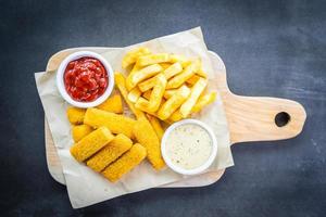 dedo de peixe e batatas fritas com molho de ketchup e maionese foto