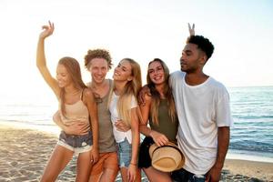 grupo do amigos tendo Diversão em a de praia. conceito do horário de verão foto