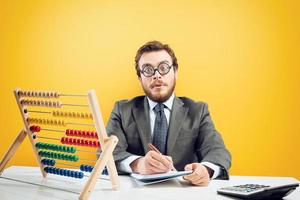 nerd contador faz Cálculo do companhia receita em amarelo fundo foto