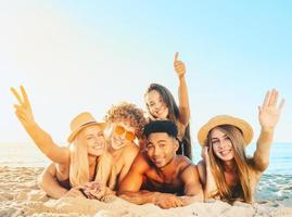 grupo do amigos tendo Diversão em a de praia foto