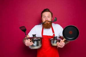 feliz chefe de cozinha com barba e vermelho avental é pronto para cozinhar foto