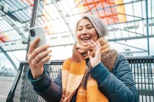 Senior mulher estão Falando com amigos através da Smartphone foto
