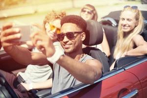 jovem amigos levar uma selfie dentro uma cabriolet carro foto
