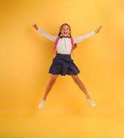 jovem menina aluna saltos Alto feliz para a promoção. amarelo fundo foto