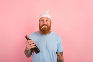 feliz homem com barba e tatuagens atos gostar uma pequeno recém-nascido bebê com Cerveja dentro mão foto