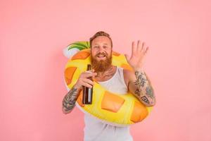 feliz homem é pronto para nadar com uma rosquinha salva-vidas com Cerveja e cigarro dentro mão foto