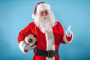 positivo santa claus com futebol bola dentro mão foto