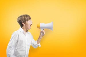 criança gritando em a megafone em amarelo fundo foto