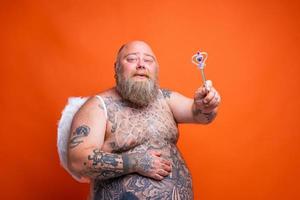 gordo feliz homem com barba , tatuagens e asas atos gostar a Magia fada foto