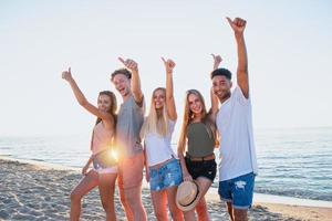 grupo do amigos tendo Diversão em a de praia. conceito do horário de verão foto