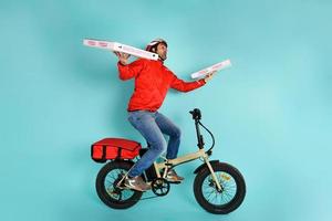 entregador corre velozes com elétrico bicicleta para entregar pizza foto