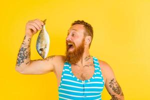 homem com barba e roupa de banho apanhado uma peixe foto