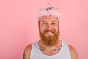 feliz homem com barba , tatuagens e coroa atos gostar uma Princesa foto