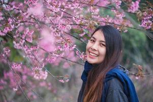 jovem ásia mulher com selvagem himalaia cereja florescendo dentro a jardim em primavera foto