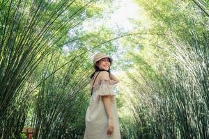 jovem ásia mulher vestindo chapéu em pé dentro bambu floresta às campo foto