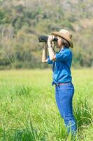 mulher usa chapéu e segura binóculo no campo de grama foto