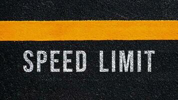 Rapidez limite escrito e amarelo linha em a estrada dentro meio do a asfalto estrada, Rapidez limite palavra em rua. foto