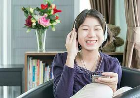 jovem mulher asiática cabelo curto ouvindo música na sala de estar foto