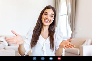 atraente jovem mulher sorridente e olhando às Câmera enquanto tendo vídeo chamar. conectados ensino. jovem mulher vestindo fone de ouvido foto