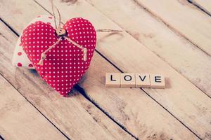 coração tecido e madeira texto do amor em de madeira mesa fundo. foto